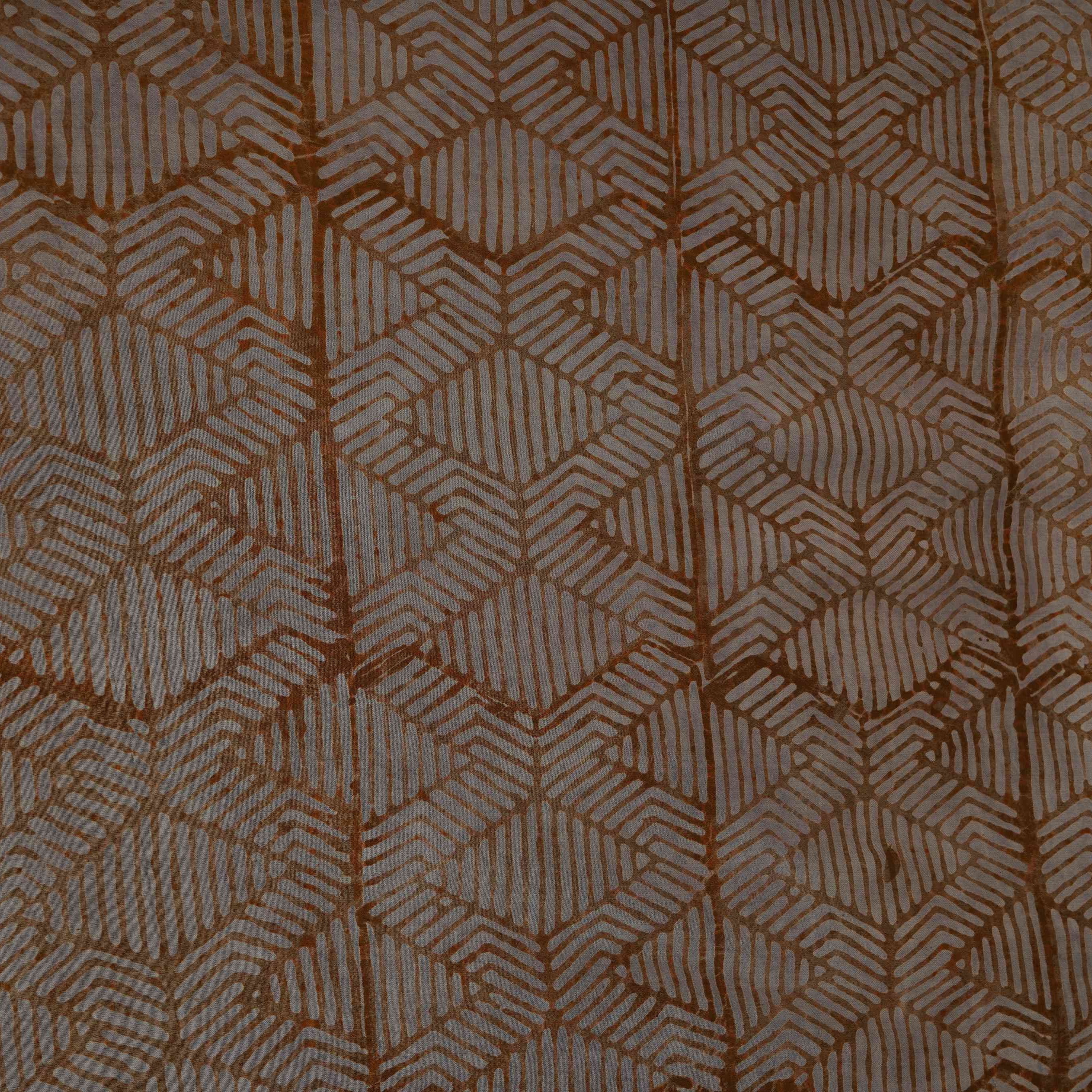 Dark mustard geometric batik print light modal satin fabric with a smooth, lustrous sheen, ideal for ethnic wear.