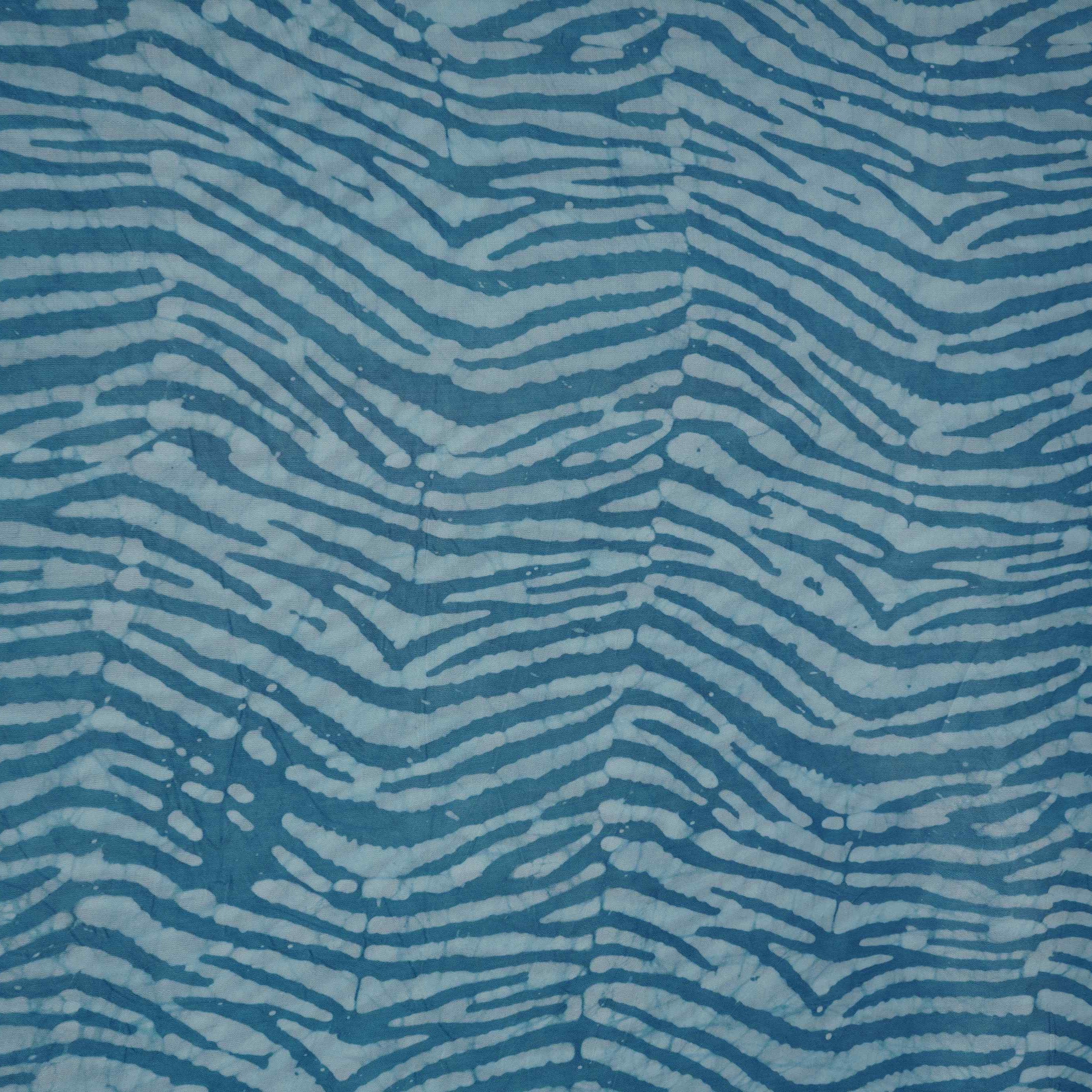 Sky blue batik print light modal satin fabric with a smooth, lustrous sheen, ideal for ethnic wear.