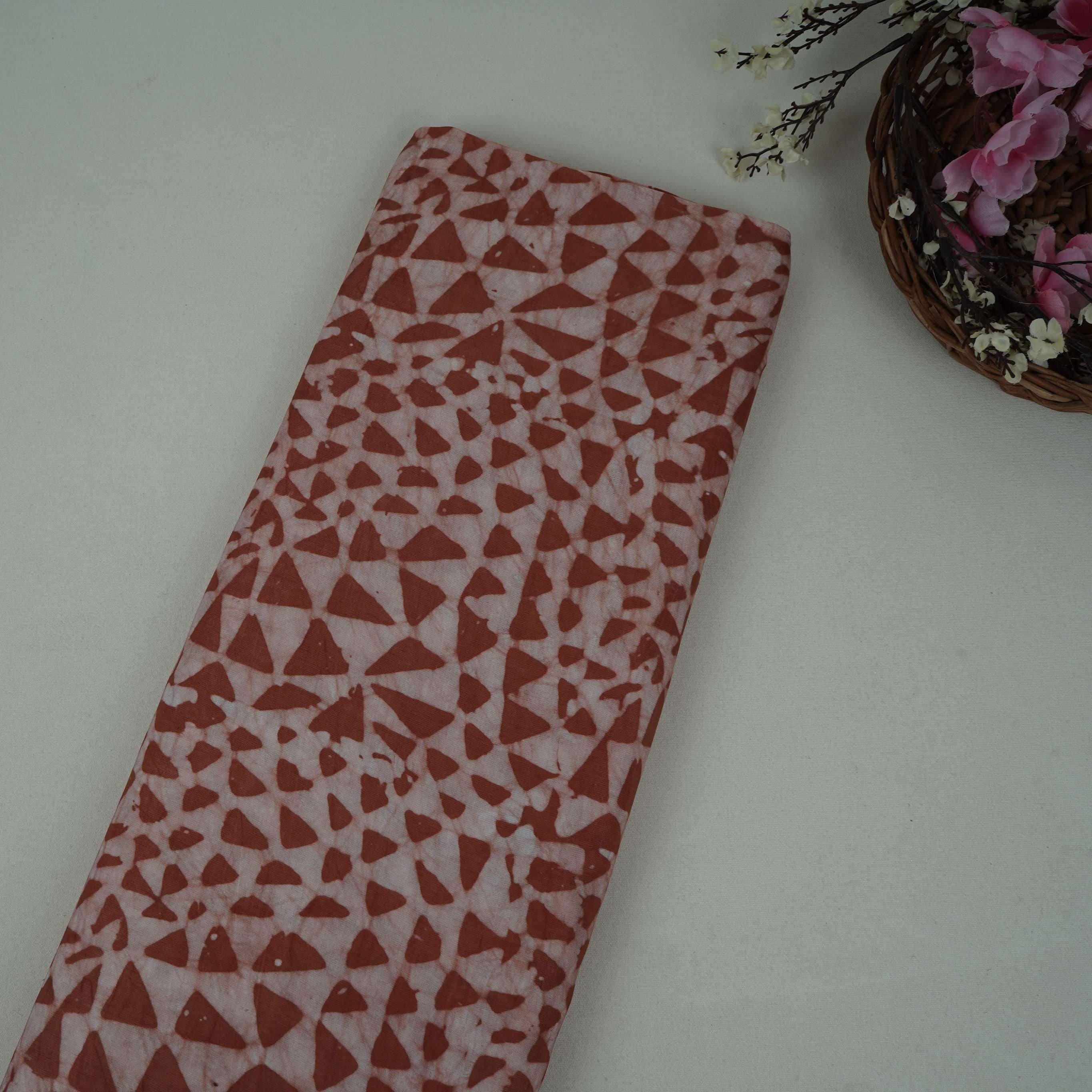 Rust brown geometric batik print light modal satin fabric with a smooth, lustrous sheen, ideal for ethnic wear.
