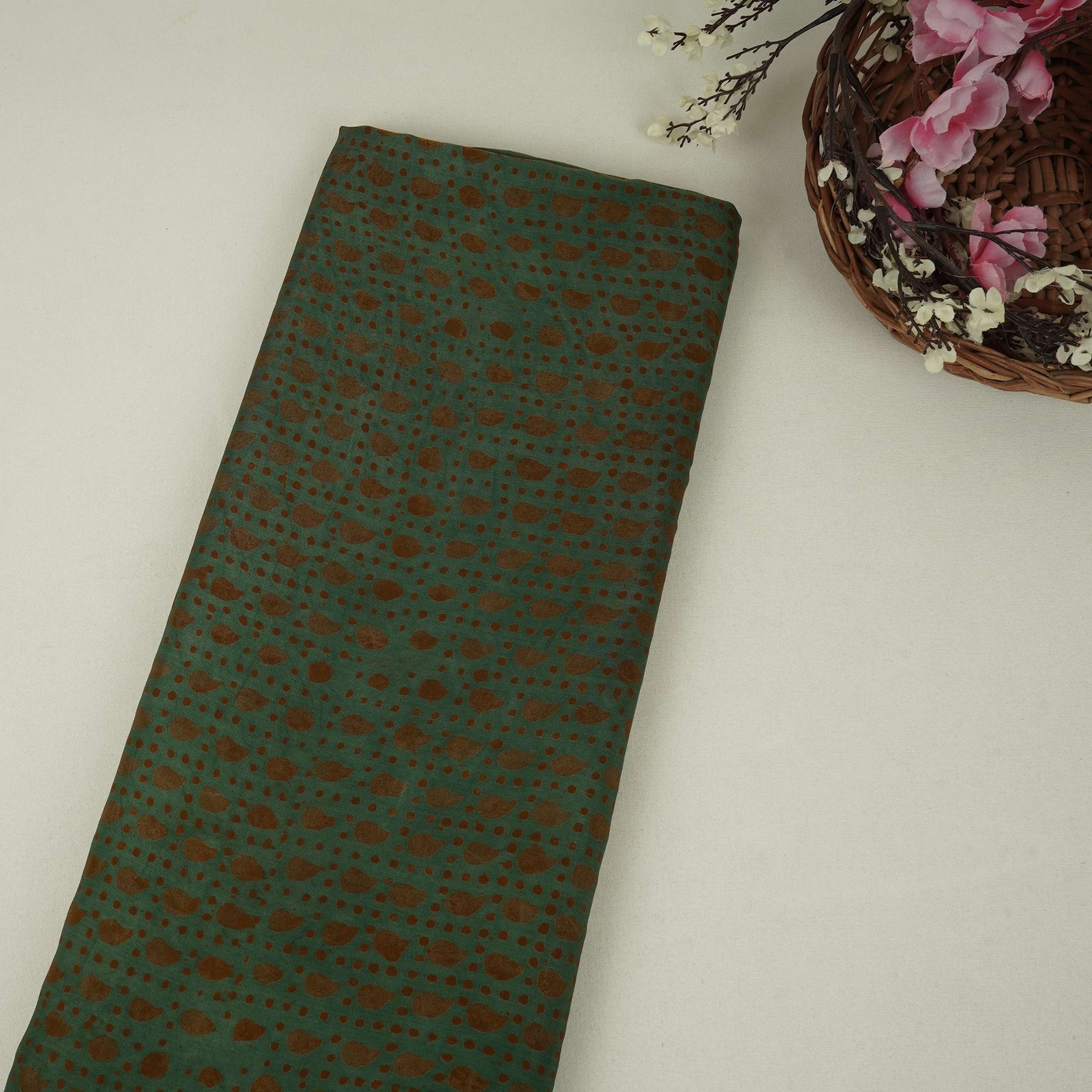 Dark green batik print light modal satin fabric with a smooth, lustrous sheen, ideal for ethnic wear.