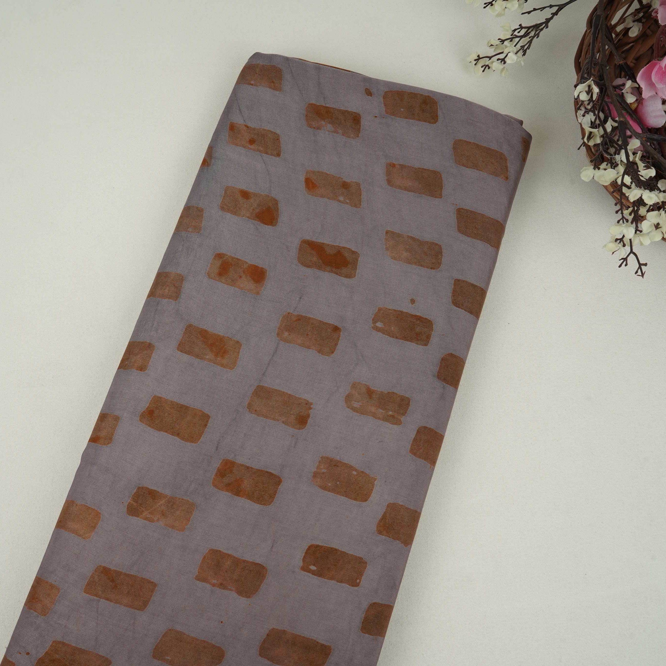 Grey block batik print light modal satin fabric with a smooth, lustrous sheen, ideal for ethnic wear.