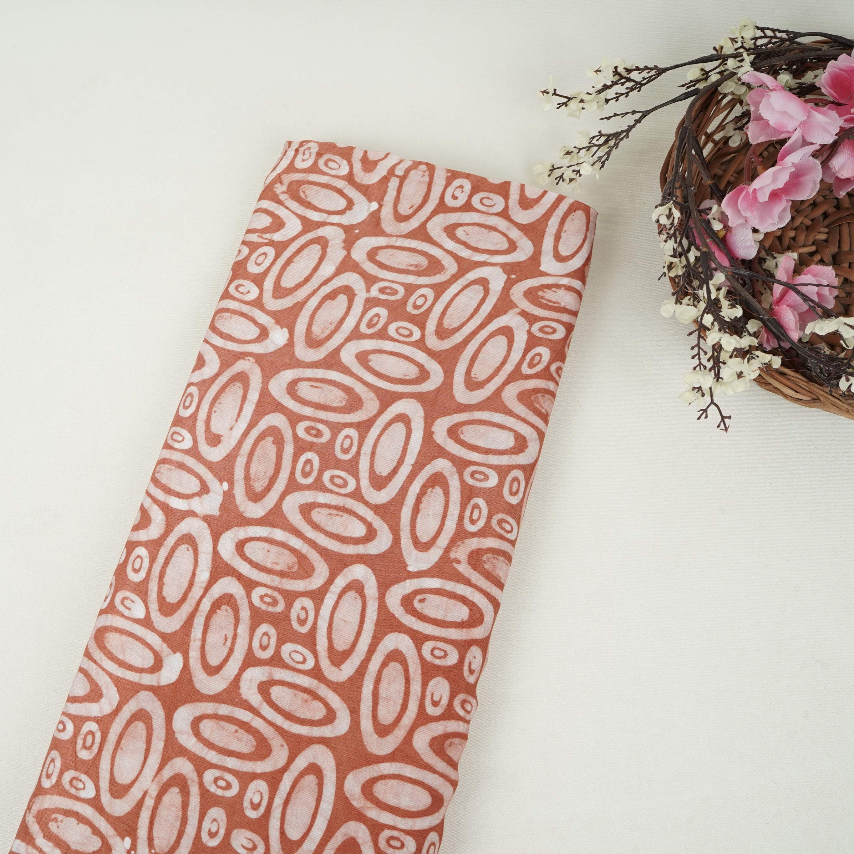 Rust brown circle batik print light modal satin fabric with a smooth, lustrous sheen, ideal for ethnic wear.