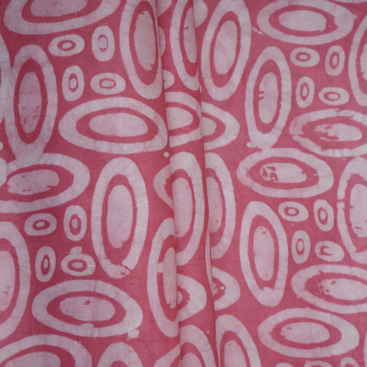 Pink circle batik print light modal satin fabric with a smooth, lustrous sheen, ideal for ethnic wear.